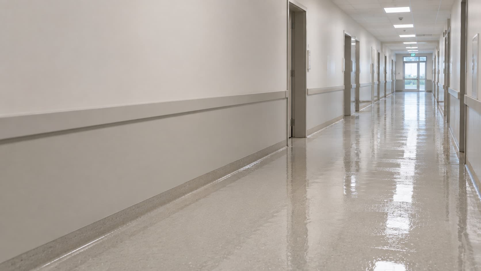 Pasillo institucional recién lavado, con el piso todavía húmedo.